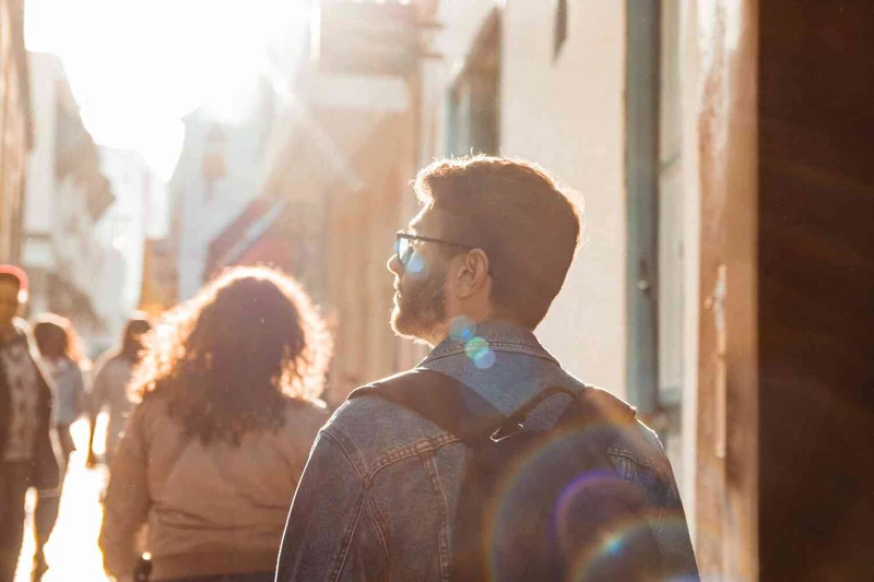 Man wandert durch die Stadt w&auml;hrend Sonne auf ihn scheint